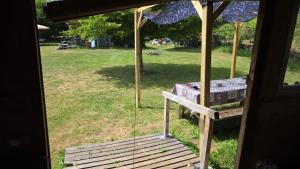 a porch with a swing and a table in a field at Le Dômes du Ceyssoux in Le Brignon