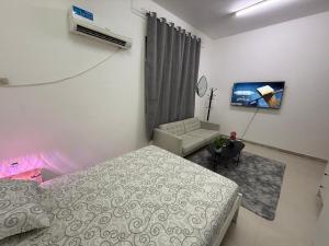 a bedroom with a bed and a couch and a tv at المرور ابو ظبي in Abu Dhabi