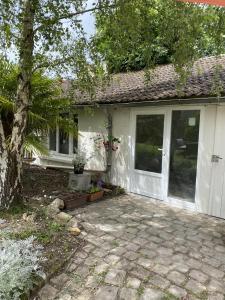 a white house with a patio and a tree at La Félicité in Boissy-le-Sec