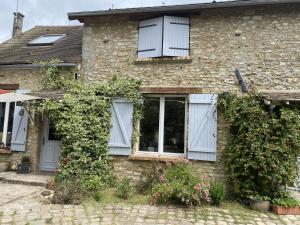 a brick house with white windows and ivy at La Félicité in Boissy-le-Sec