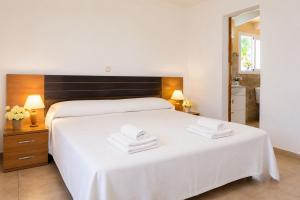 a bedroom with a large white bed with towels on it at Villa Roca Nova in Cacla D'or