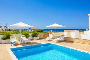 a swimming pool with chairs and umbrellas at Villa Diana Seaside in Pomos