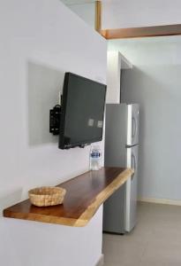 a flat screen tv hanging on a wall next to a refrigerator at Samanu Hotel & Suites in Sayulita