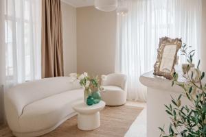 a living room with a white couch and a chair at AMAREA BOUTIQUE Hotel in Eforie Sud