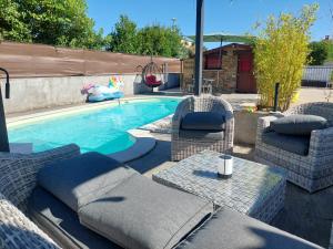 a swimming pool with wicker chairs and a table next to it at Chalet proche aéroport de Bastia in Lucciana
