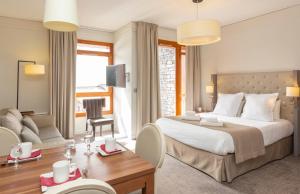 a bedroom with a large bed and a living room at Hôtel Eden by Odalys in Arc 1800 +53 photos