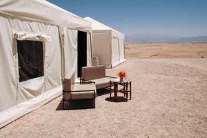 a tent with two chairs and a table in the desert at Agafay Camping in Aït Daoud
