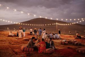 a group of people sitting on the ground at night at Agafay Camping in Aït Daoud
