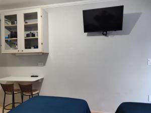 a room with a tv and a table and chairs at kitnet individual Campinas in Campinas