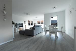 a living room with a couch and a table at Salz & Seele Das Spa Ferienhaus mit Whirlpool, Sauna & Wallbox in Büsum