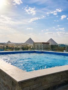 a swimming pool with pyramids in the background at Marquis Pyramids Hotel in Cairo