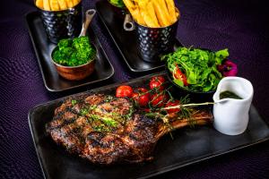 a steak on a black plate with vegetables and fries at The Glenmoriston Townhouse Hotel in Inverness