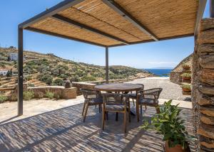 a patio with a table and chairs and a view of the ocean at Lithoskino Suites in Batsi