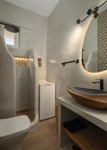 a bathroom with a sink and a toilet and a mirror at Lithoskino Suites in Batsi