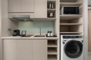 a kitchen with a washing machine and a sink at Oakwood Studios Sukhumvit Bangkok in Bangkok