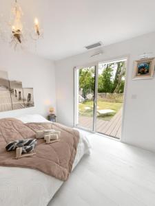 a white bedroom with a large bed and a large window at Villa Émeraude Spa in Le Porge +13 photos