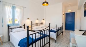 two beds in a room with a kitchen at Lume d'Oro Syros in Kini
