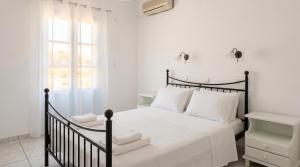 a bedroom with a black bed with white sheets and a window at Lume d'Oro Syros in Kini +48 photos