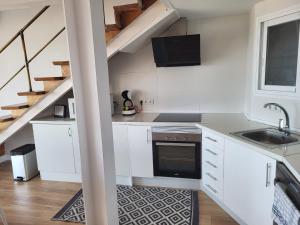 a kitchen with white cabinets and a sink and a staircase at Levante Frontline Luxury Duplex 5 Bedrooms in Benidorm