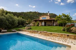 a villa with a swimming pool in front of a house at Blue Jasmine Villa - Private Pool and Garden in Aigio