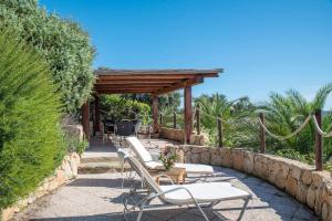 a patio with white chairs and a stone wall at Résidence Villa Smeralda in Telti