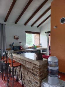 a kitchen with a brick counter with stools at Hospedaje Casa Campestre Pistacia Vera - Villa de Leyva in Villa de Leyva