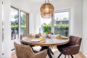 a dining room with a table with chairs and a chandelier at FeWo Lieblingsplatz in Zingst +18 photos