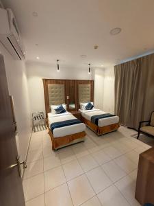 a hotel room with two beds and a chair at جراند سيزون للشقق الفندقية الخبر Grand Season Hotel Apartments in Al Khobar in Al Khobar