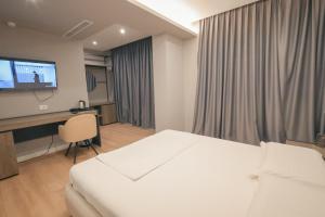 a bedroom with a bed and a desk and a television at The Real Sea View Hotel Vlore in Vlorë