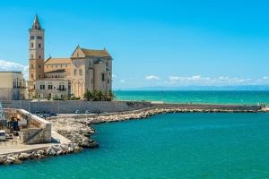 a building with a clock tower next to a body of water at Maison Arche' relax e spazio a Sannicandro in Sannicandro di Bari