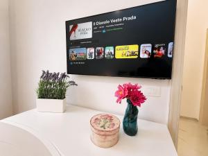 a white table with a vase of flowers and a tv at Maison Arche' relax e spazio a Sannicandro in Sannicandro di Bari
