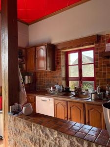a kitchen with wooden cabinets and a red ceiling at Chambre d'Hôte des Arcs in Coulonces