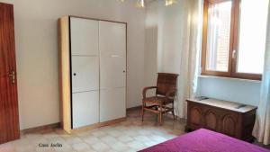a bedroom with a large white cabinet and a chair at Appartamento Mancaversa Centro, 200m mare in Marina di Mancaversa
