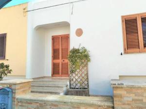 a white house with a red door and a plant at Appartamento Mancaversa Centro, 200m mare in Marina di Mancaversa