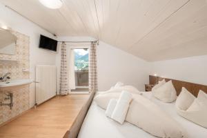 a bedroom with a bed with white sheets and a window at Haus St. Christoph in Mayrhofen