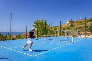 a man is playing tennis on a tennis court at Passione Mare in Porto Palo