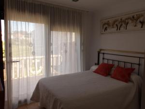a bedroom with a bed with red pillows and a window at Ave del Mar in Camariñas