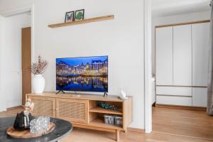 a living room with a television on a wooden entertainment center at Helt ny leilighet in Leknes