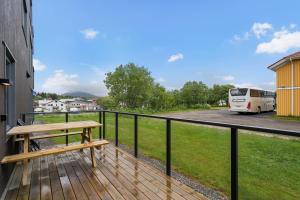 a wooden deck with a bench on the side of a building at Helt ny leilighet in Leknes