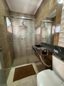 a bathroom with a shower and a toilet and a sink at Pousada das Águas in Lambari