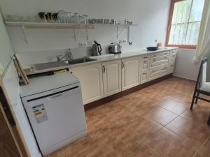 a kitchen with white cabinets and a sink and a dishwasher at Občerstvení u cyklostezky in Břehov +11 photos