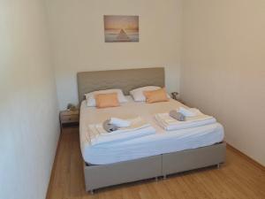 a bedroom with a large bed with white sheets and orange pillows at Apartman Daniela in Neum