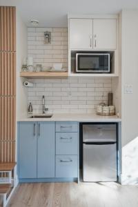 a kitchen with blue cabinets and a microwave at Low Tide Suite - Modern, Oceanside Suite with King Bed, Resort Pool & Hot Tub in Nanoose Bay