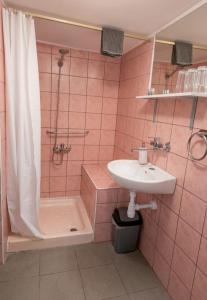a pink tiled bathroom with a sink and a shower at C&M Studio Apartment in Rijeka