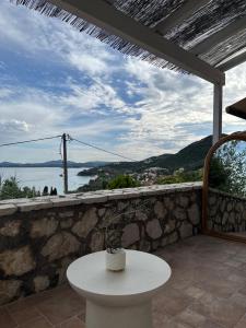 a white table on a stone wall with a view of the water at Aura di Mare in Barbati