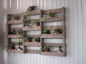 a wooden shelf with potted plants on a wall at Albergo La Genzianella in Miasino