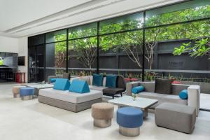 a lobby with couches and tables and windows at Oakwood Studios Sukhumvit Bangkok in Bangkok