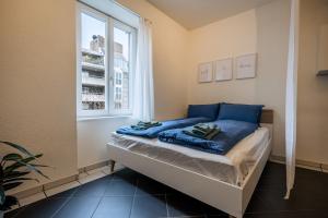 a bed with blue sheets in a room with a window at Gemütliches Studio im Stadtzentrum in Biel