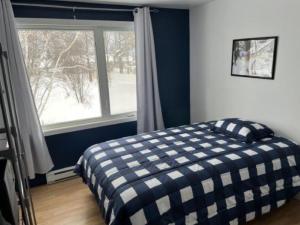 a bedroom with a checkered bed in front of a window at Maison de chambres - Édifice Le SAGE in Shawinigan +10 photos