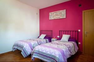 two beds in a room with pink walls at Hostal Papi in Zafrilla